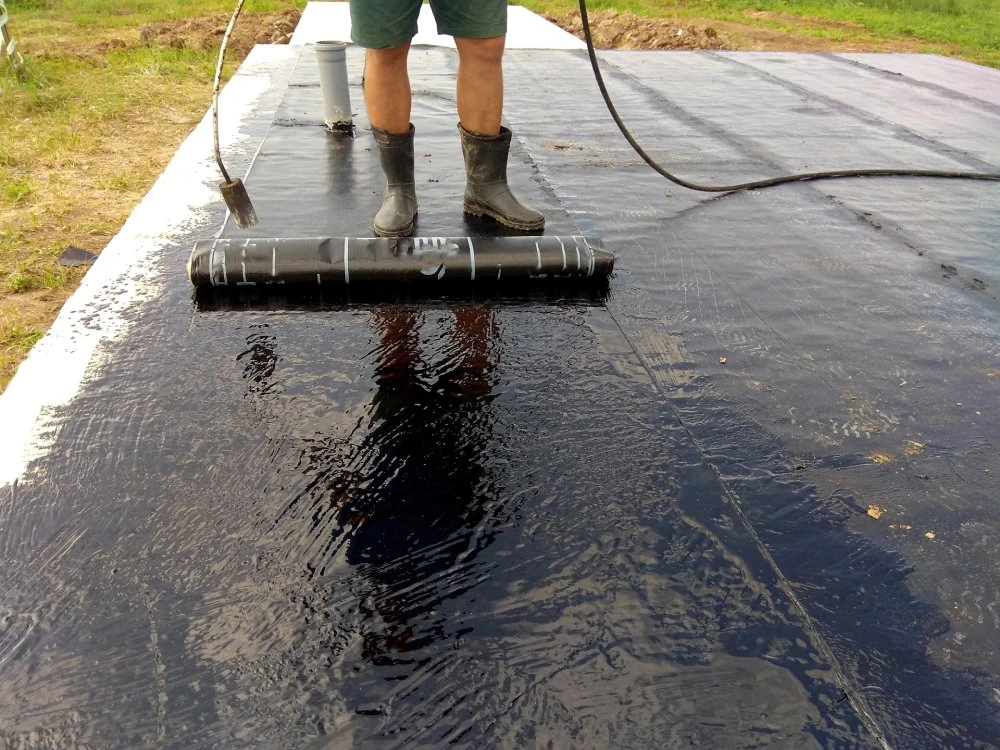 Roofer paints bituman